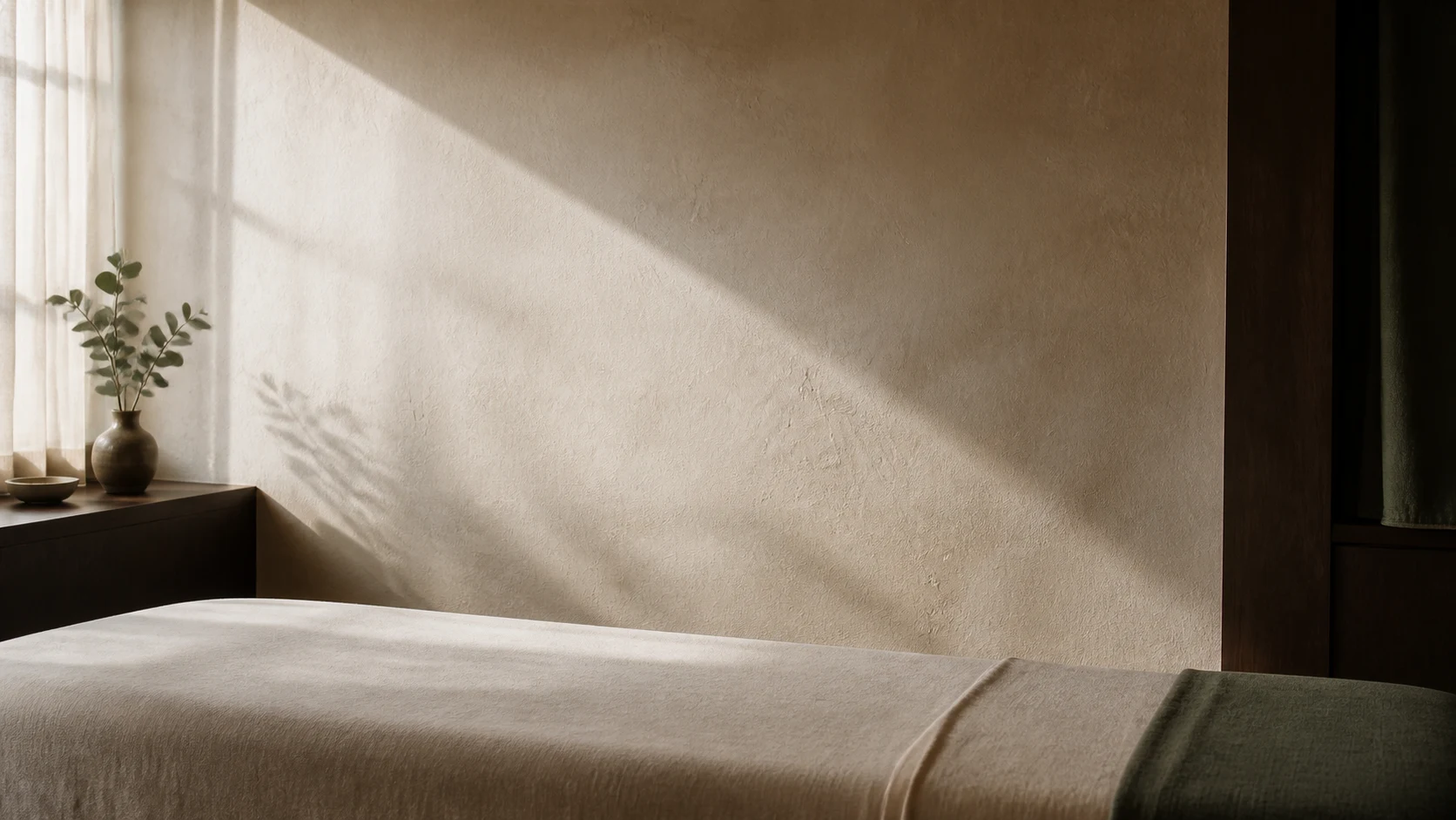 Warm late-afternoon light across a prepared massage table in an imagined private studio