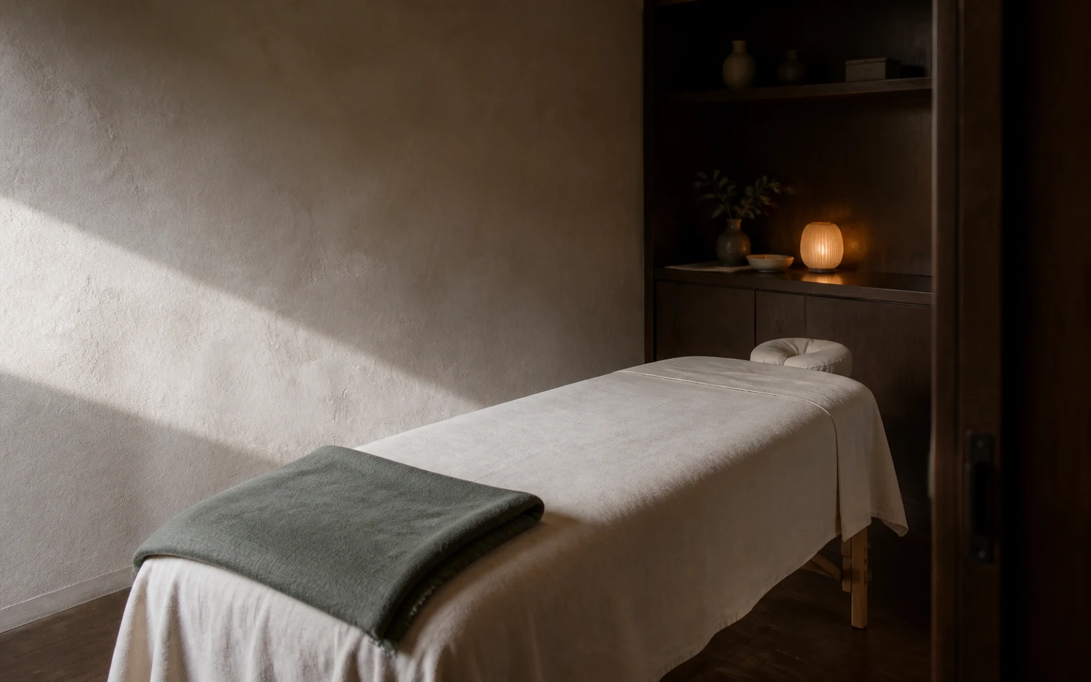 Prepared massage table in an imagined compact mineral and timber private studio